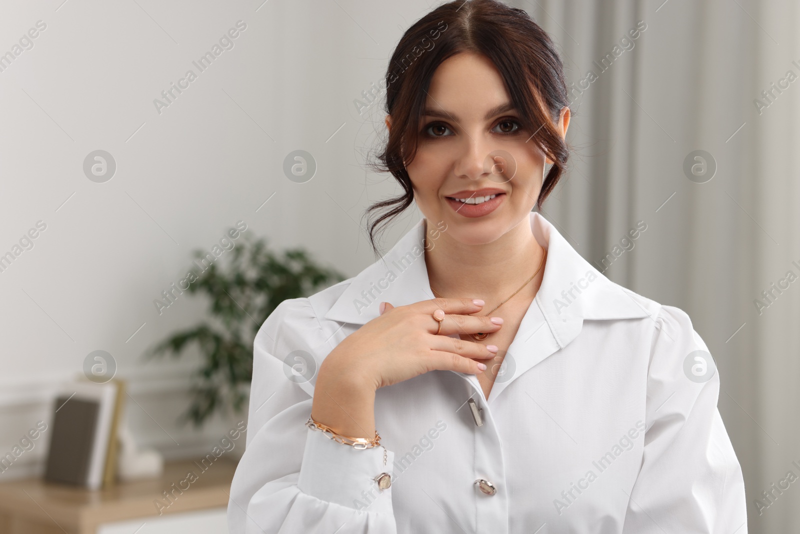 Photo of Beautiful young woman wearing elegant jewelry indoors