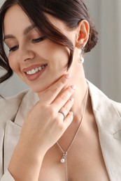 Photo of Beautiful young woman wearing elegant jewelry indoors, closeup