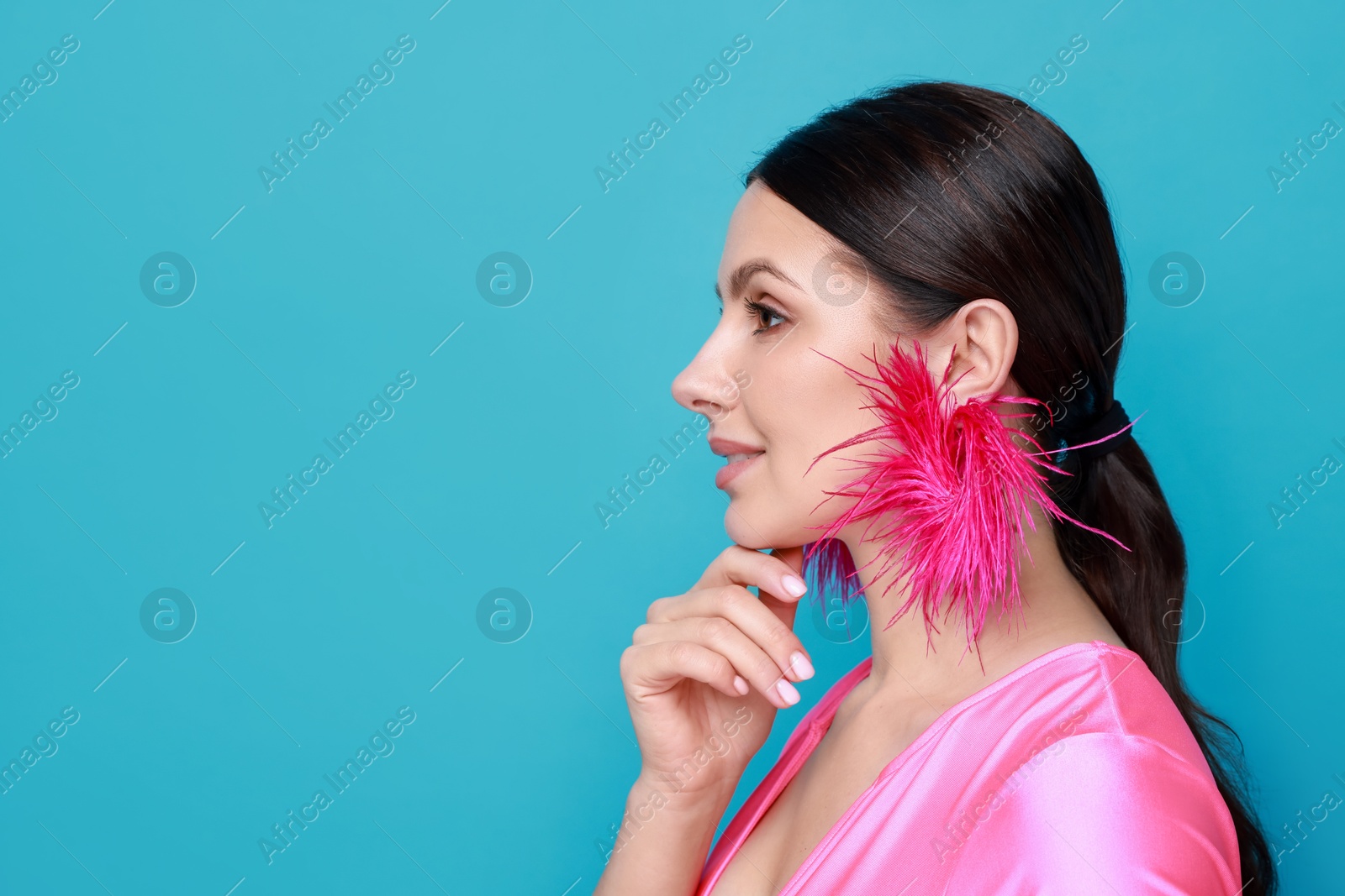 Photo of Beautiful young woman wearing stylish earrings on light blue background. Space for text