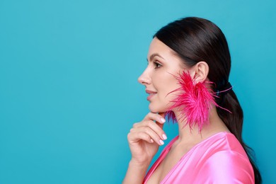 Photo of Beautiful young woman wearing stylish earrings on light blue background. Space for text