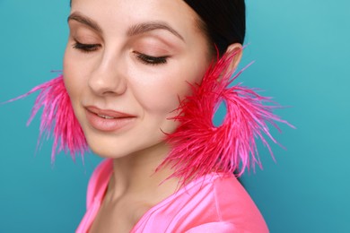 Photo of Beautiful young woman wearing stylish earrings on light blue background, closeup