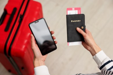 Photo of Traveller with passport, flight tickets and smartphone indoors, above view