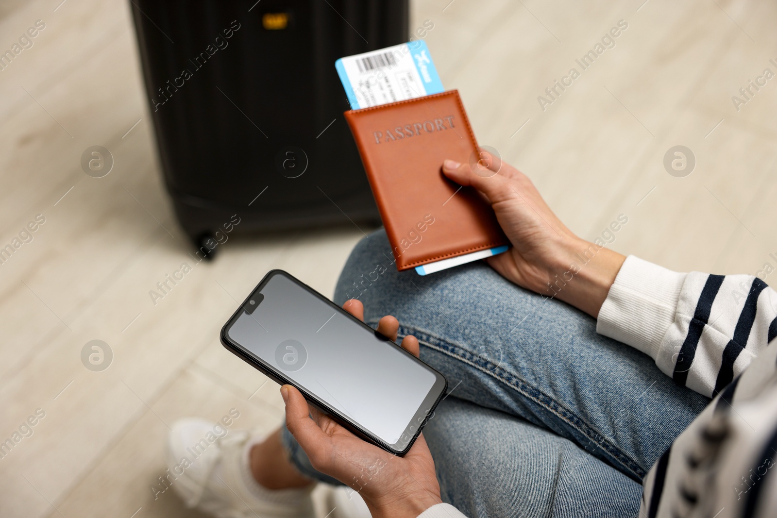 Photo of Traveller with passport, flight ticket and smartphone indoors, closeup