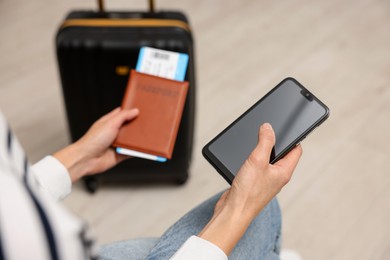 Traveller with passport, flight ticket and smartphone indoors, closeup