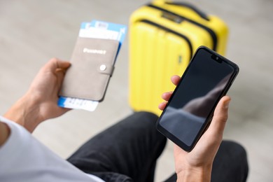 Photo of Traveller with passport, flight tickets and smartphone indoors, closeup