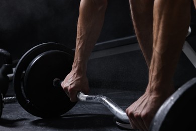 Man with talcum powder on hands training with barbell in gym, closeup