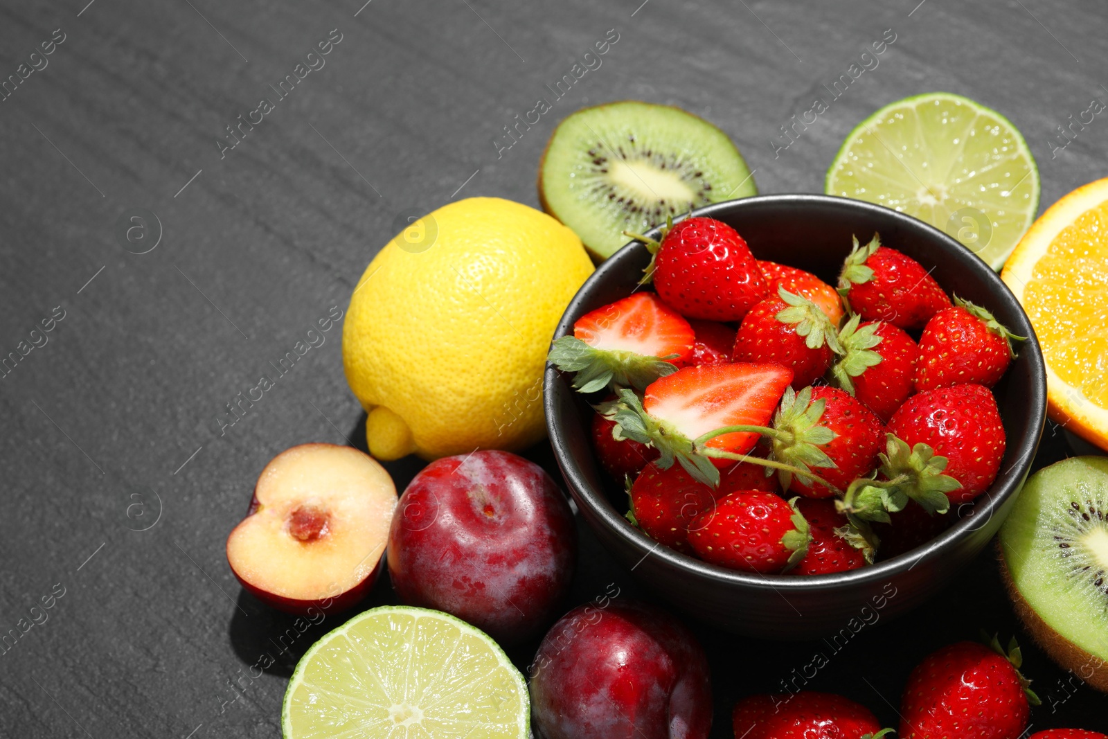 Photo of Different fresh fruits on grey textured table, closeup