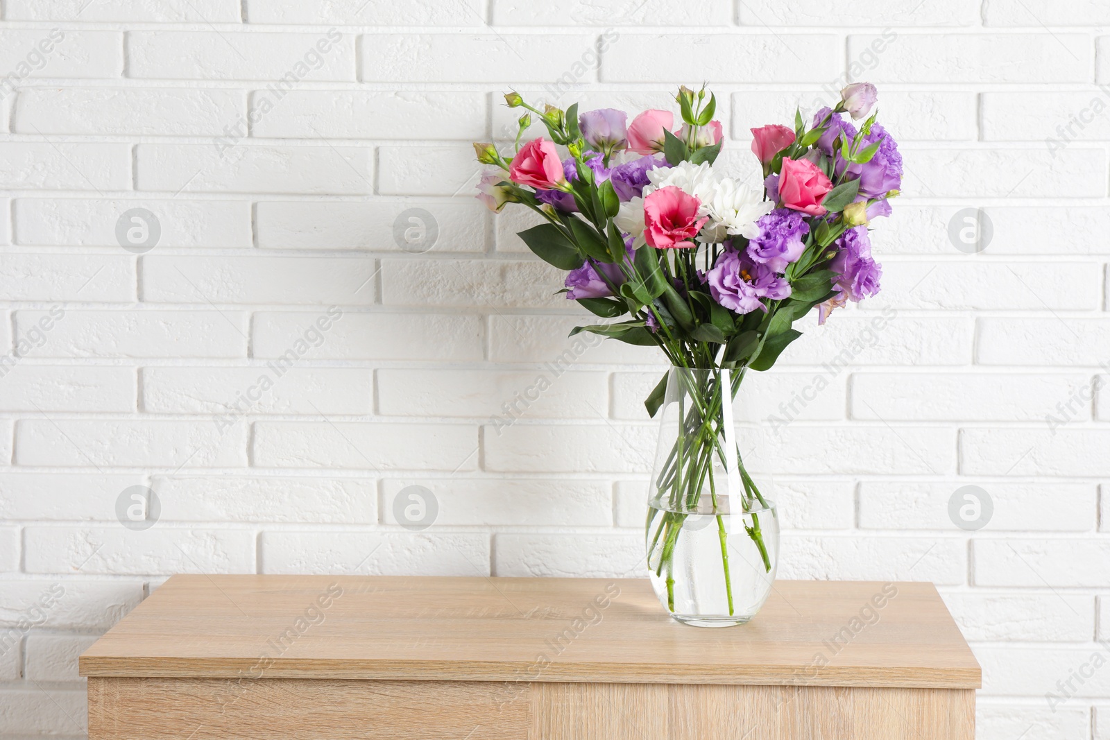 Photo of Vase with beautiful eustoma flowers on wooden chest of drawers, space for text