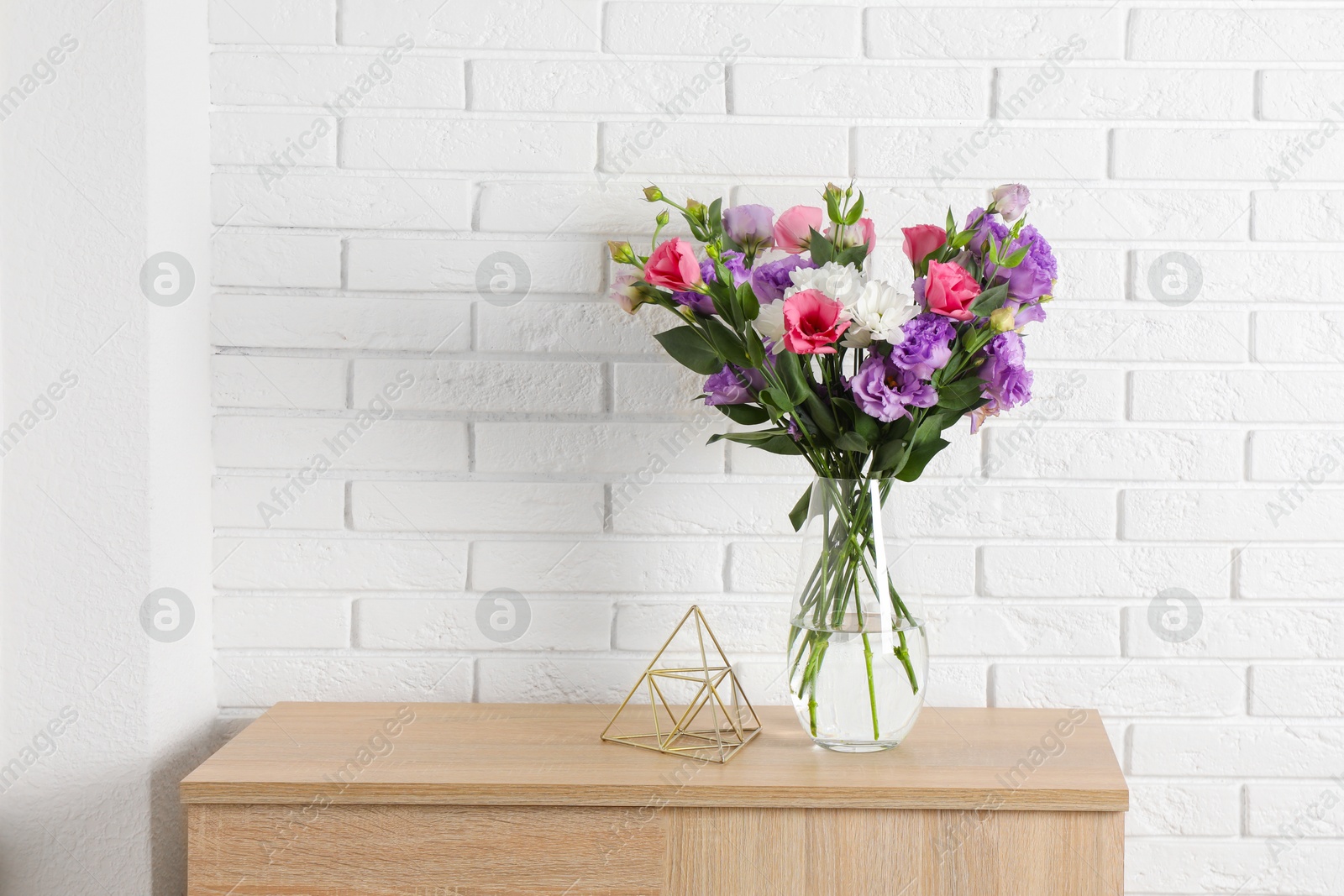 Photo of Vase with beautiful eustoma flowers on wooden chest of drawers, space for text