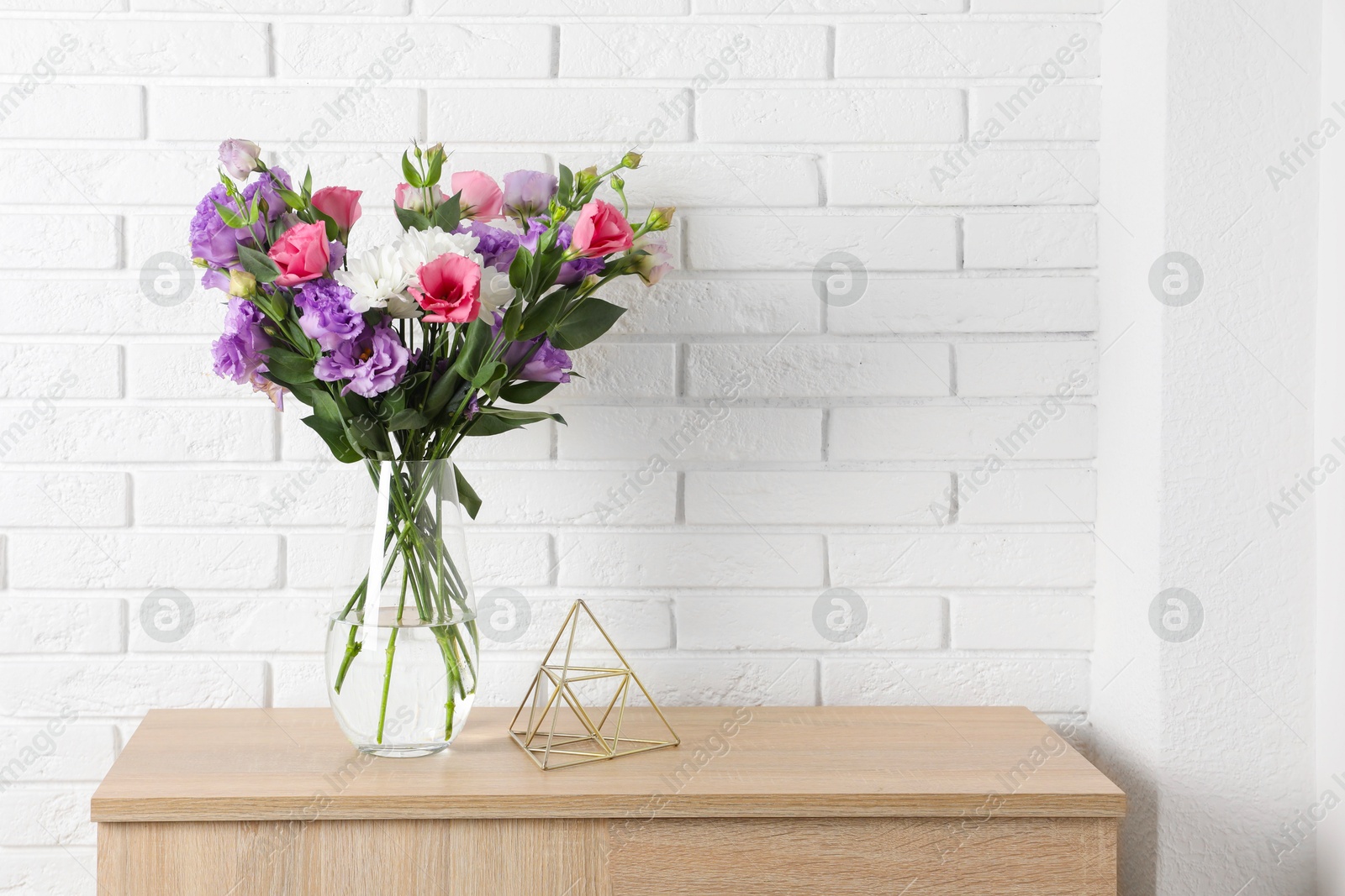 Photo of Vase with beautiful eustoma flowers on wooden chest of drawers, space for text