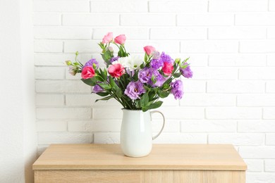 Photo of Vase with beautiful eustoma flowers on wooden chest of drawers