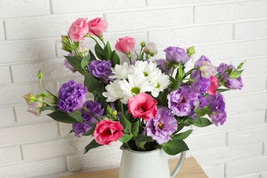 Photo of Vase with beautiful eustoma flowers near white brick wall, closeup