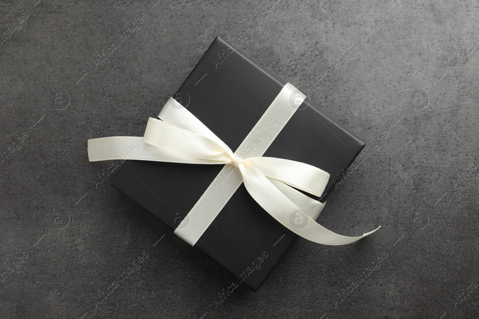 Photo of Gift box with bow on grey table, top view