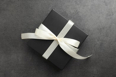 Gift box with bow on grey table, top view