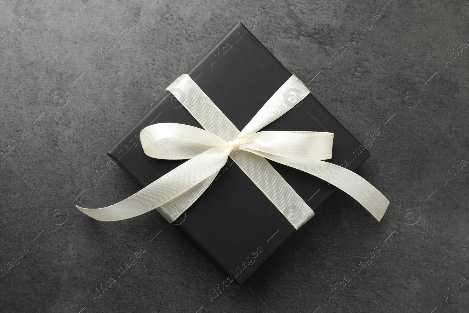 Photo of Gift box with bow on grey table, top view