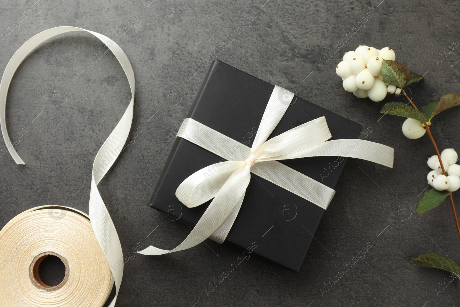 Photo of Gift box with bow, ribbon and flowers on grey table, flat lay