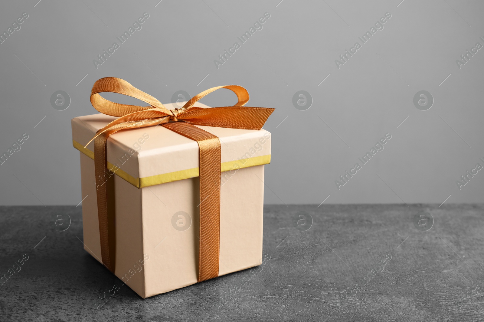 Photo of Gift box with bow on grey table, space for text