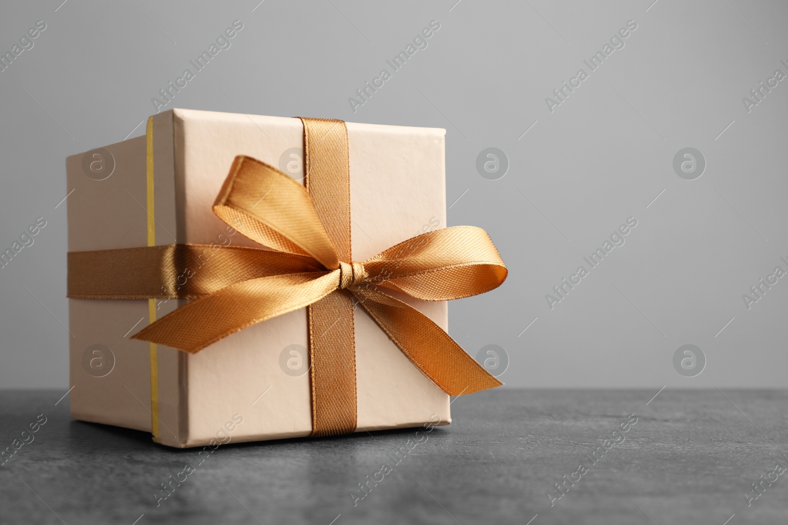 Photo of Gift box with bow on grey table, space for text