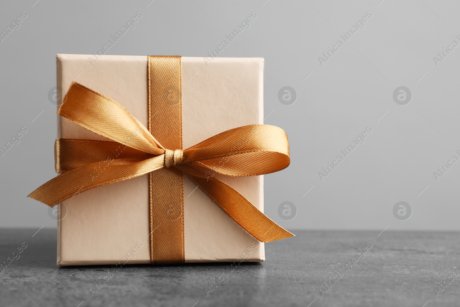 Photo of Gift box with bow on grey table. Space for text