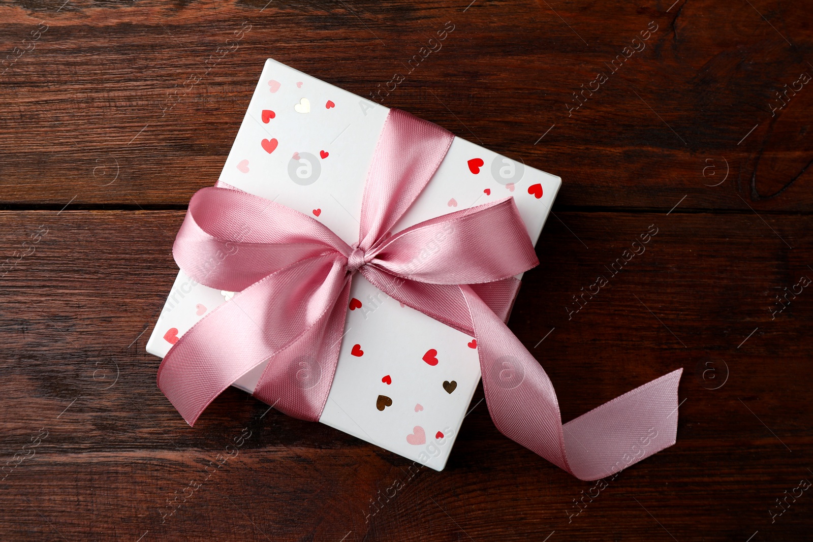 Photo of Gift box with bow on wooden table, top view