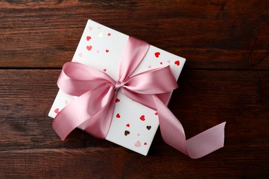 Photo of Gift box with bow on wooden table, top view