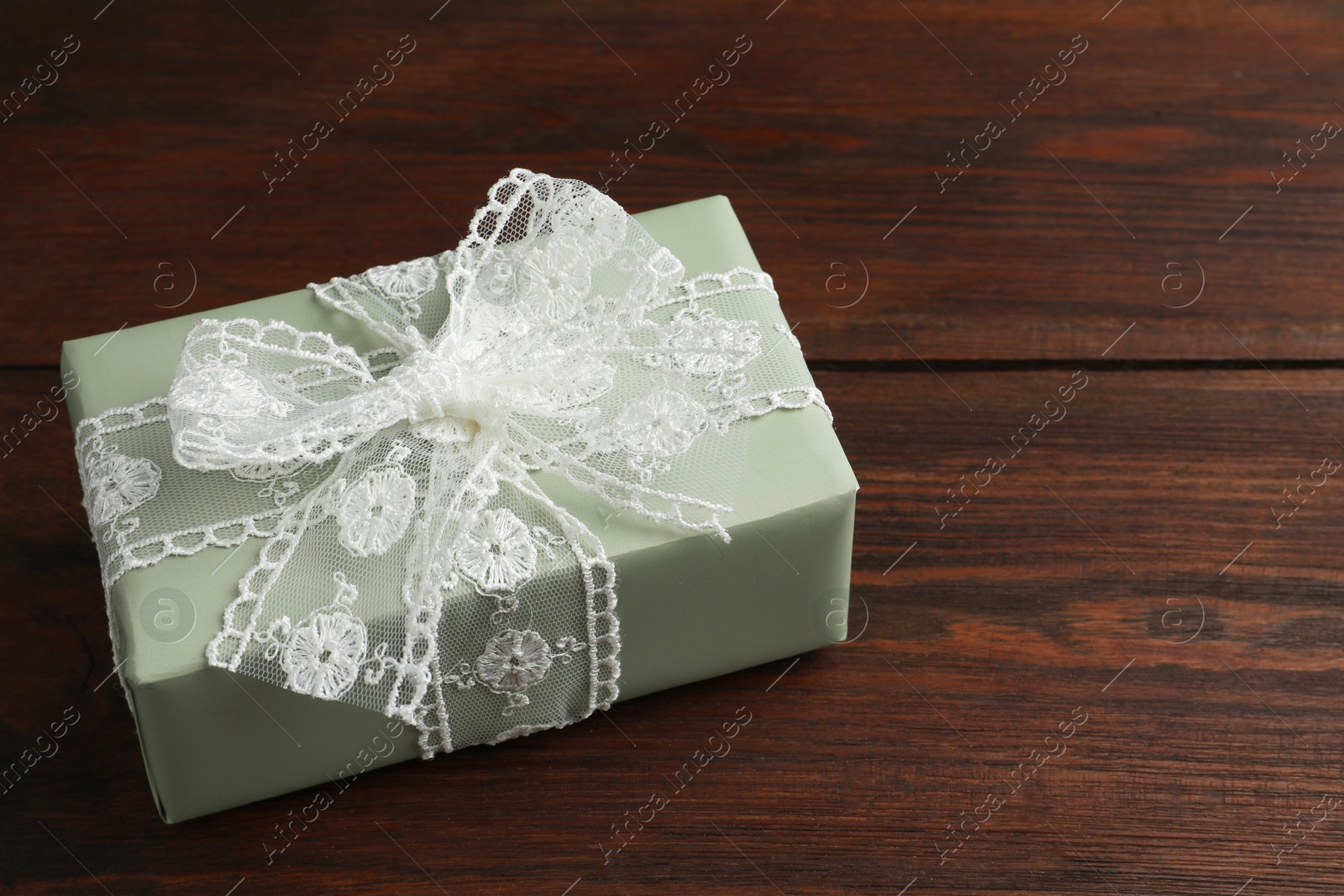 Photo of Gift box with bow on wooden table, space for text