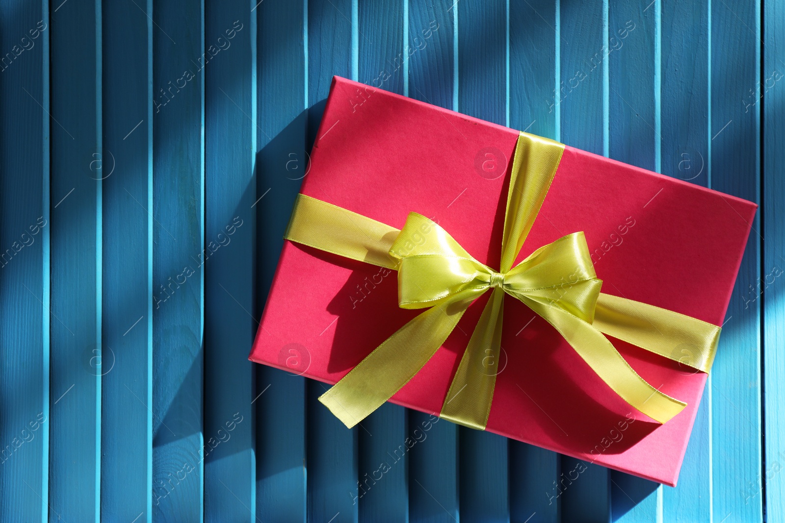 Photo of Gift box with bow on blue textured table, top view