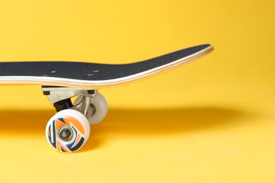 Photo of One skateboard on yellow background, closeup. Sports equipment