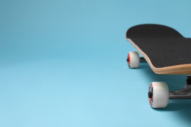 Photo of One skateboard on light blue background, closeup. Space for text