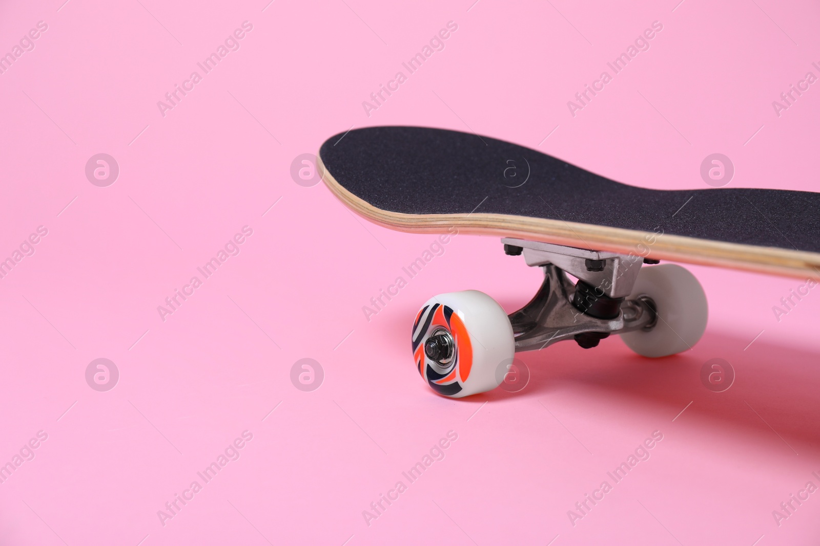 Photo of One skateboard on pink background, closeup. Space for text