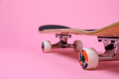 Photo of One skateboard on pink background, closeup. Space for text