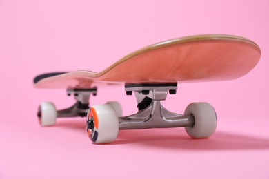 Photo of One skateboard on pink background, closeup. Sports equipment