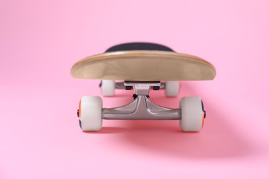 Photo of One skateboard on pink background, closeup. Sports equipment