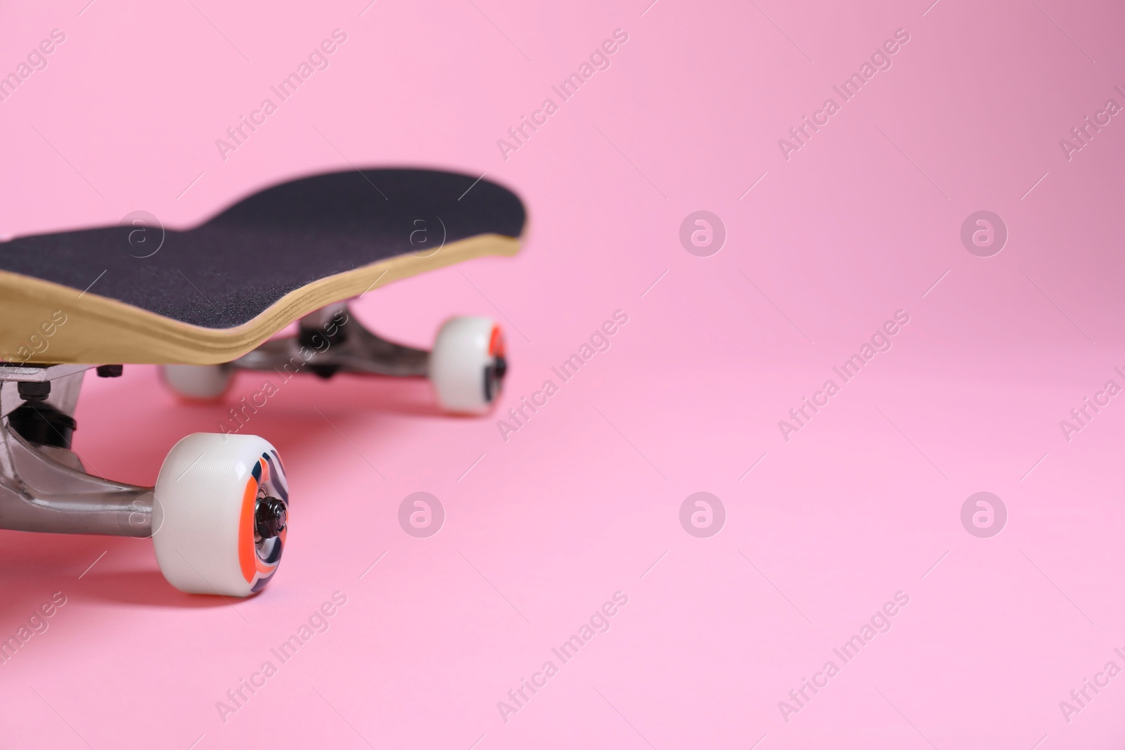 Photo of One skateboard on pink background, closeup. Space for text