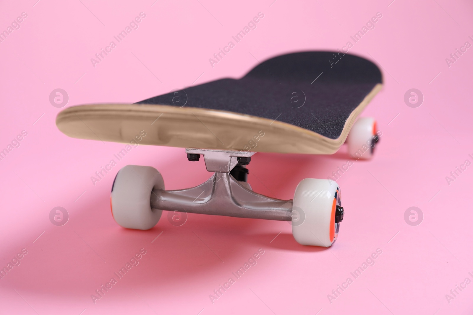 Photo of One skateboard on pink background, closeup. Sports equipment