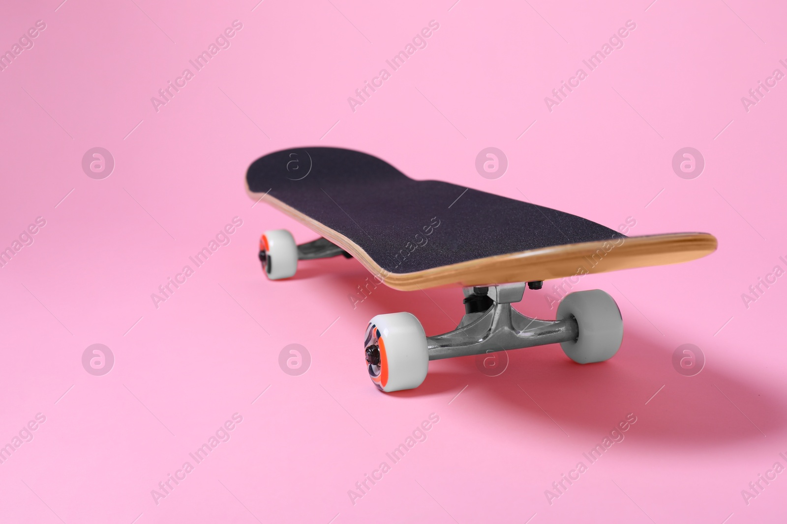 Photo of One skateboard on pink background, closeup. Space for text