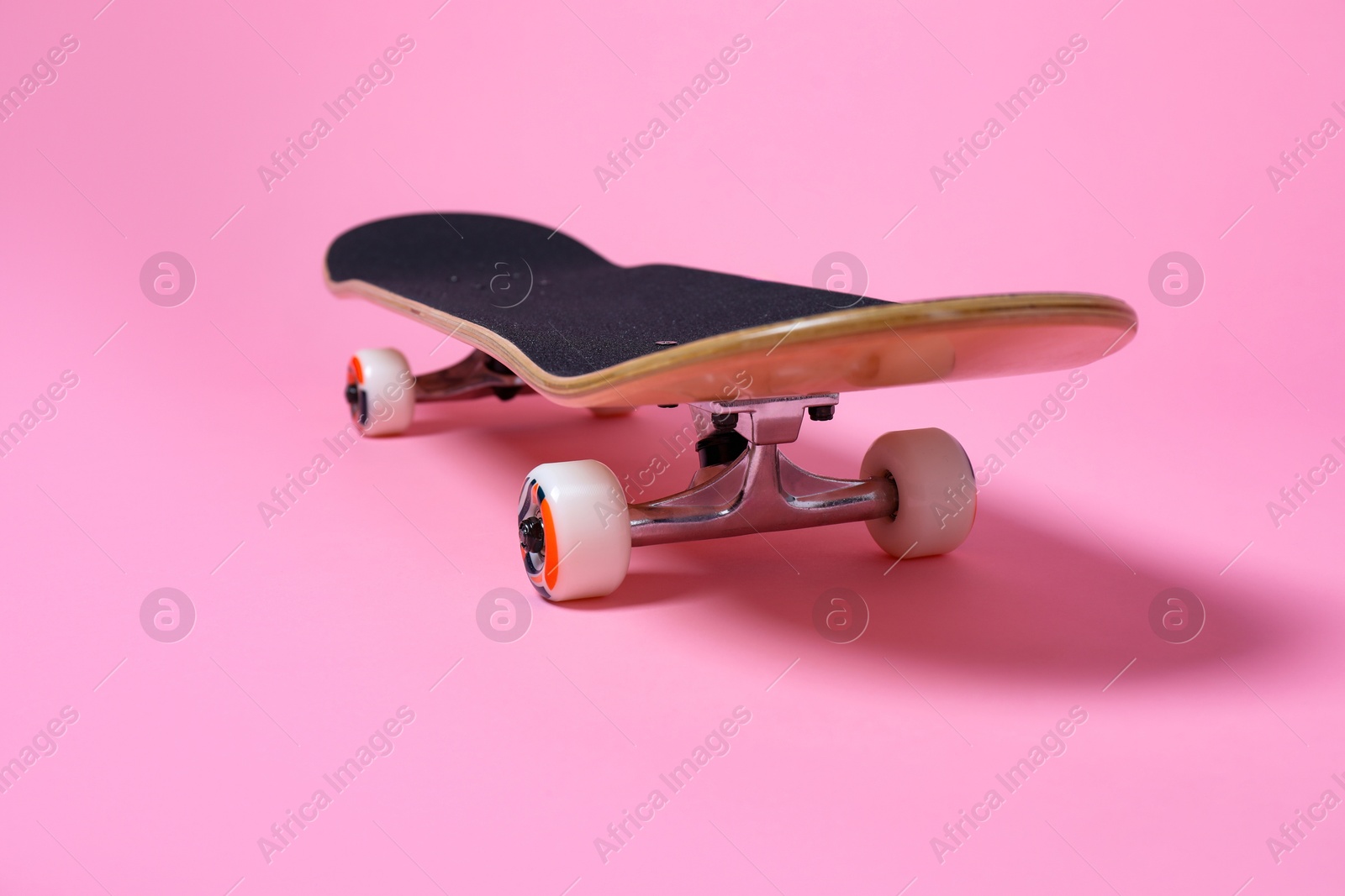 Photo of One skateboard on pink background, closeup. Sports equipment