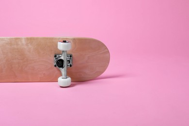 Photo of One skateboard on pink background, space for text. Sports equipment