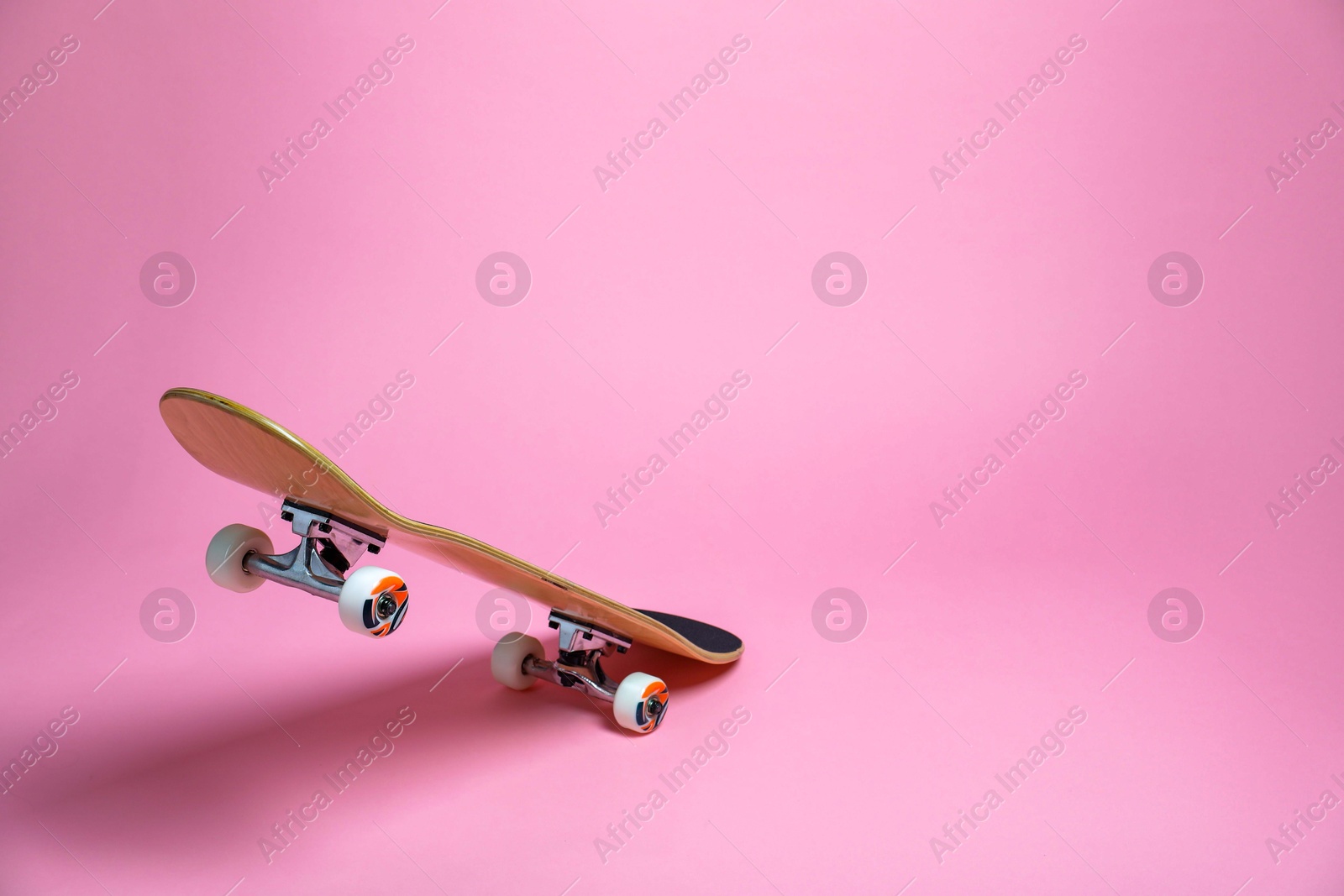 Photo of One skateboard on pink background, space for text. Sports equipment