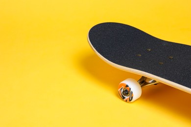 Photo of One skateboard on yellow background, closeup. Space for text