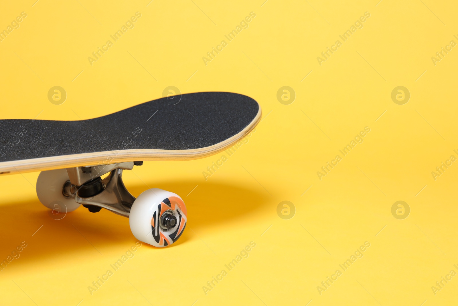 Photo of One skateboard on yellow background, closeup. Space for text