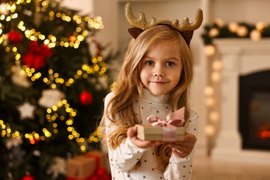 Photo of Little girl with Christmas gift at home