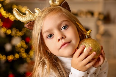 Photo of Little girl with Christmas ornament at home