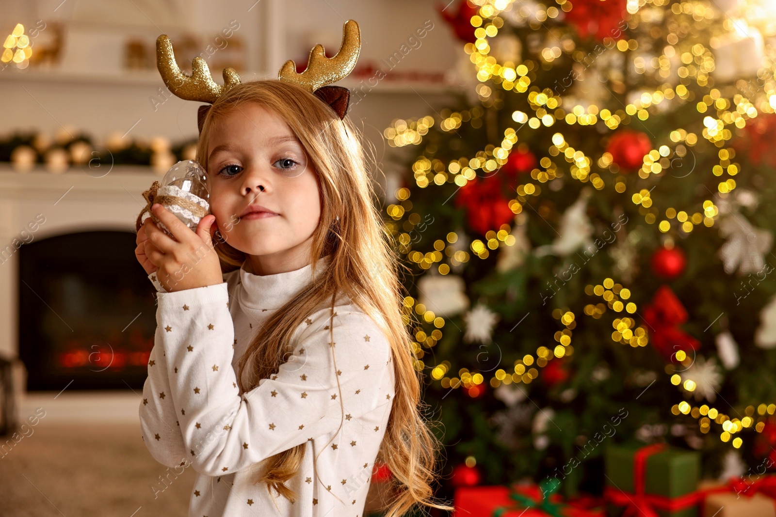 Photo of Little girl with Christmas ornament at home, space for text