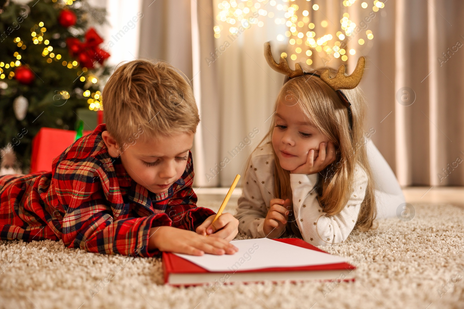 Photo of Little kids writing letter to Santa Claus on floor at home. Christmas celebration