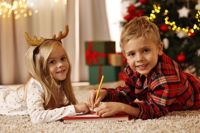 Little kids writing letter to Santa Claus on floor at home. Christmas celebration