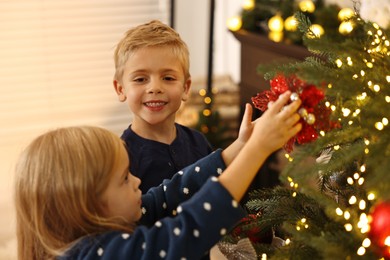 Photo of Little kids decorating Christmas tree at home