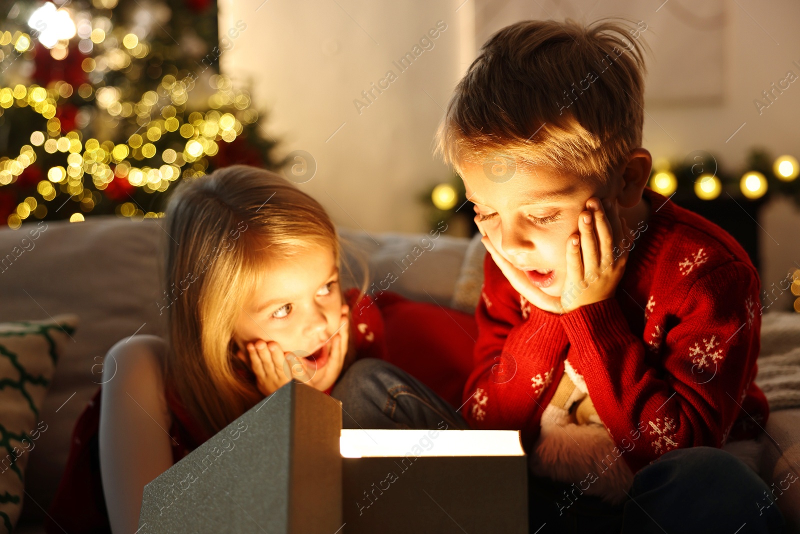 Photo of Surprised little kids near open magic Christmas box at home