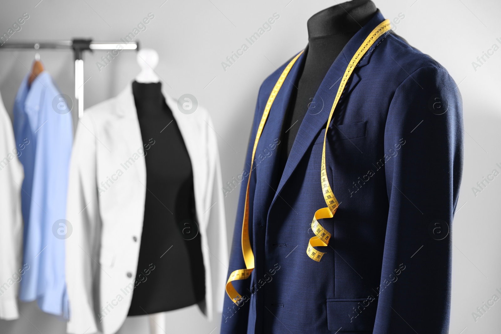 Photo of Male mannequin with jacket and measuring tape in tailor shop, closeup