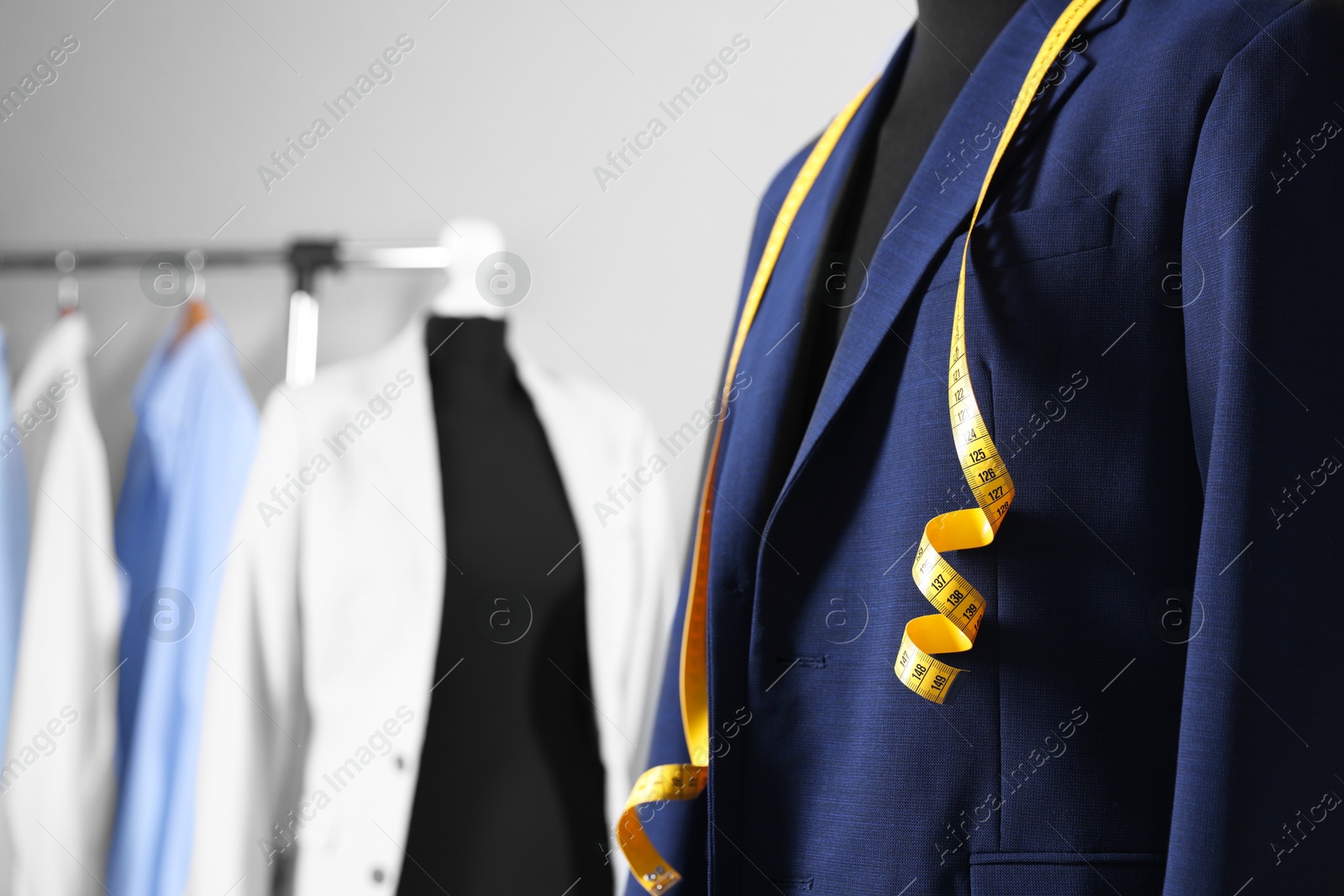 Photo of Male mannequin with jacket and measuring tape in tailor shop, closeup